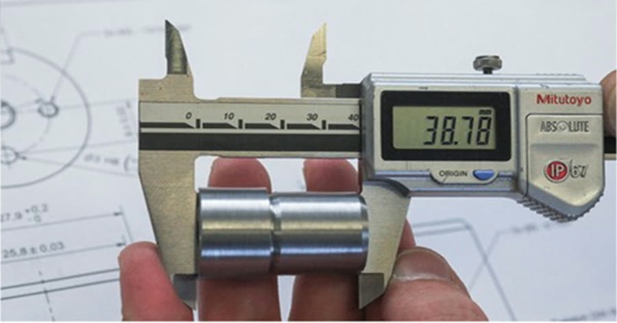 Digital caliper measuring a machined component during dimensional inspection